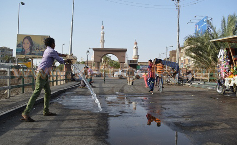 صورة لأحد المواطنين يرش المياه في الشارع 